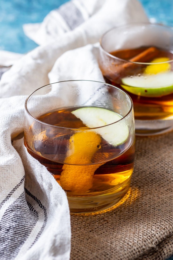 Side on shot of spiced apple cocktail with rum in a mat with a cloth