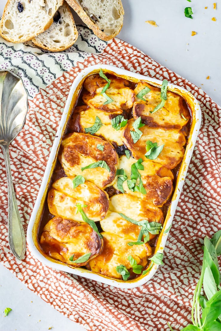 Overhead shot of halloumi bake on a patterned cloth with bread and basil