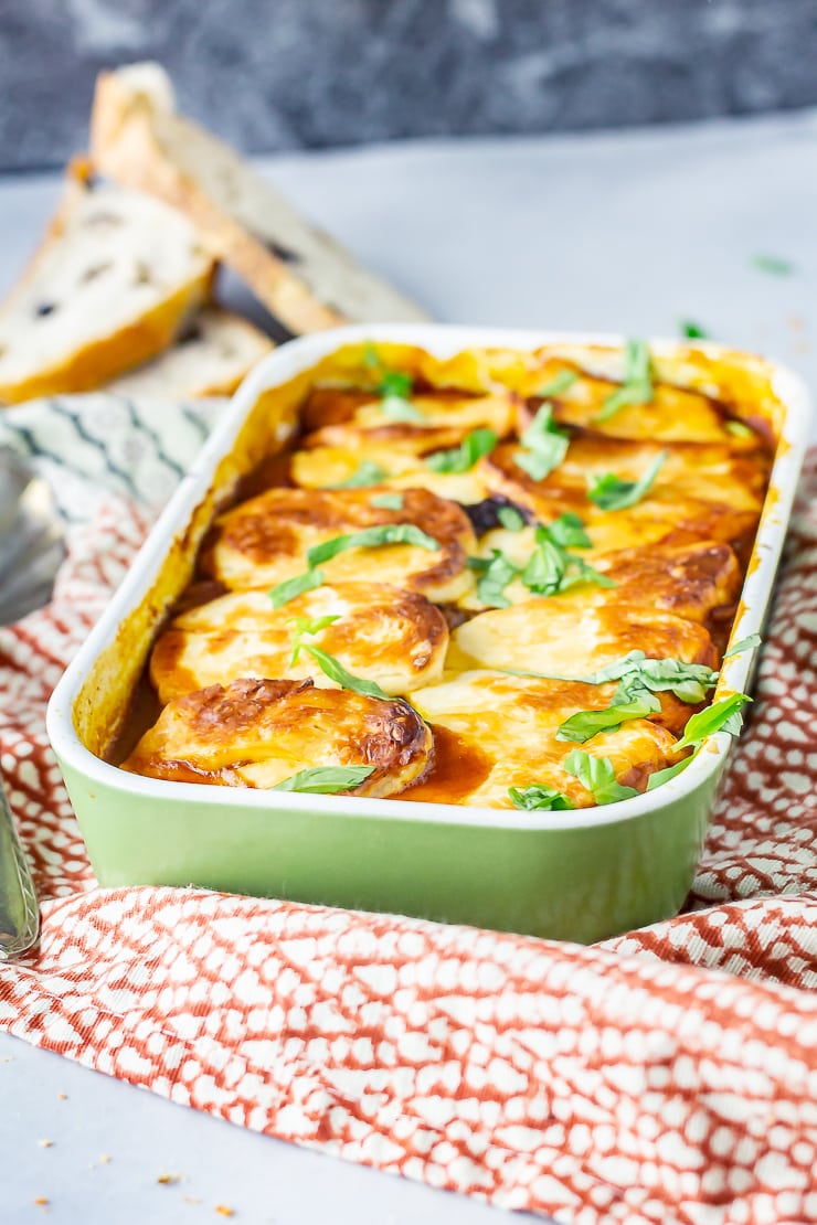 Side angle shot of halloumi bake in a green baking dish on a patterned cloth