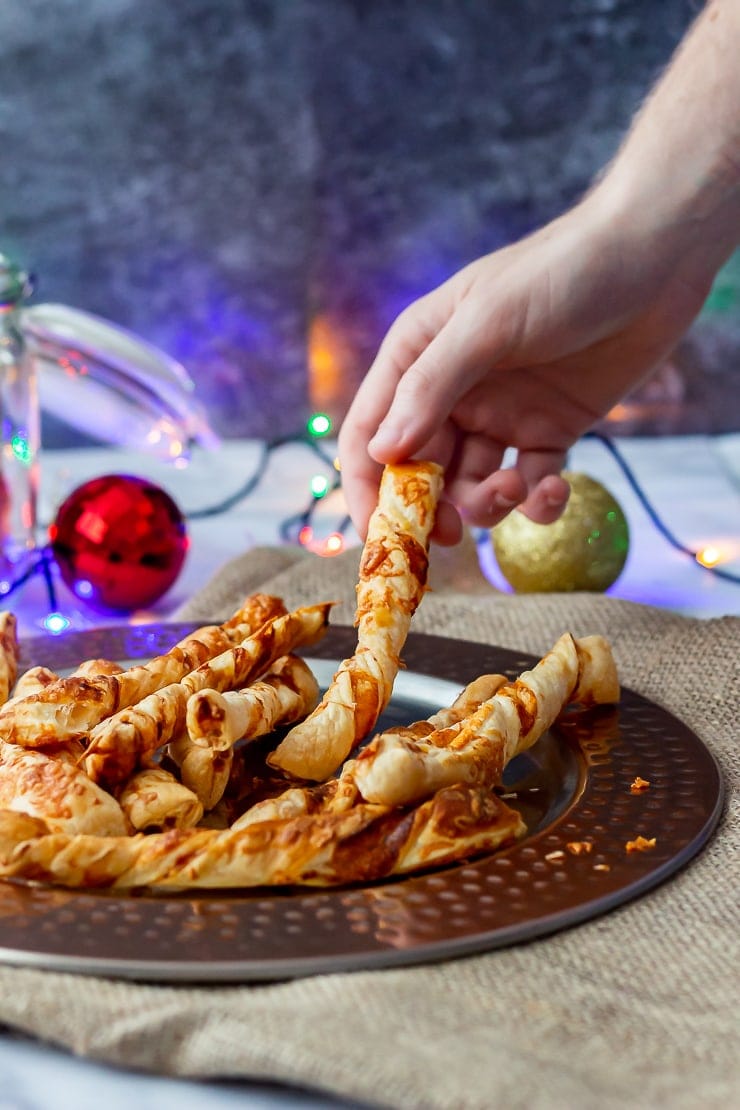 Chipotle cheese twists on a platter with a hand taking one