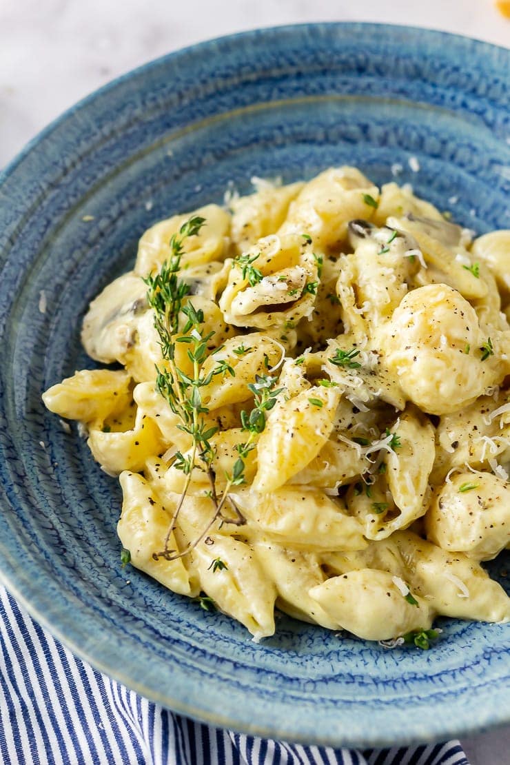 Side angle close up of creamy mushroom pasta in a blue bowl