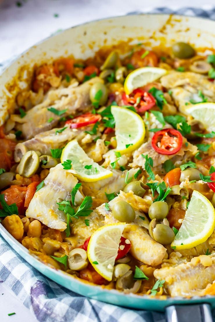 One pot fish stew in a blue frying pan with a checked cloth