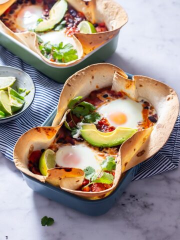 Side angle shot of huevos rancheros baked eggs on a marble background
