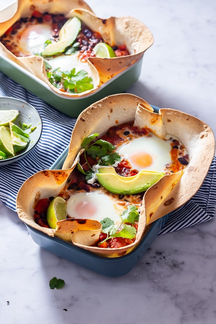 Side angle shot of huevos rancheros baked eggs on a marble background