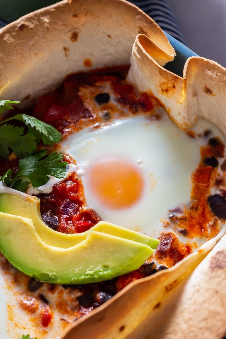 Close up of huevos rancheros baked eggs with avocado