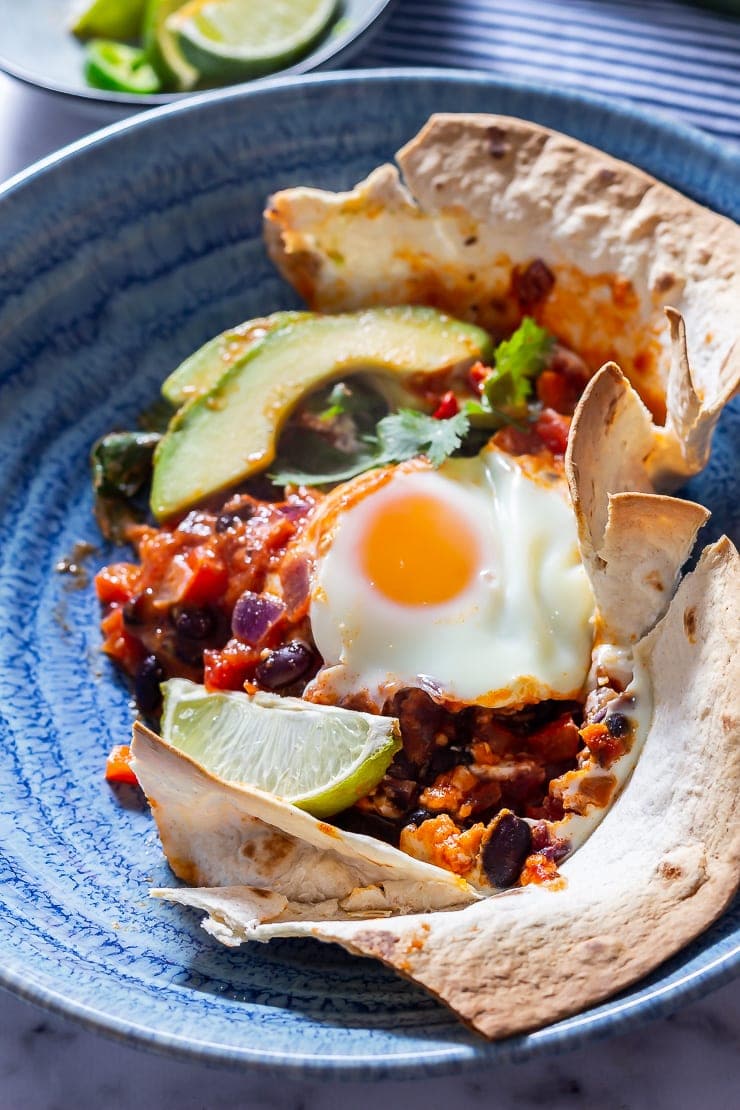 Portion of huevos rancheros baked eggs in a blue bowl