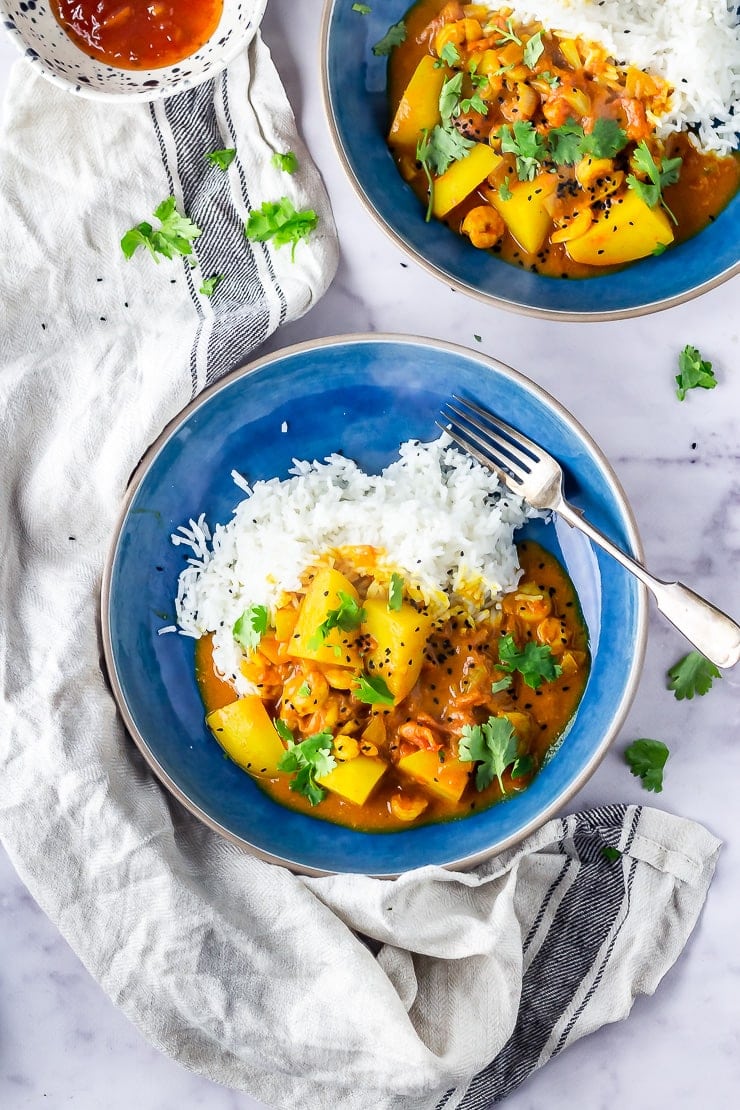 Overhead shot of creamy prawn curry with potato in a blue bowl