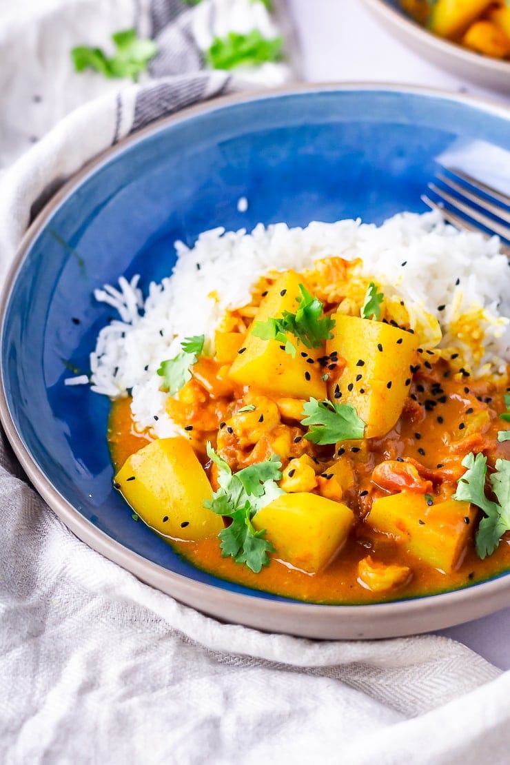 Side angle shot of prawn curry in a blue bowl with rice 