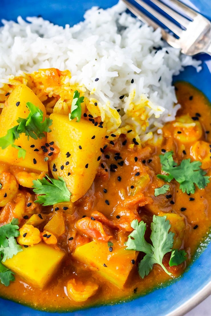 Close up of creamy prawn curry with rice in a blue bowl