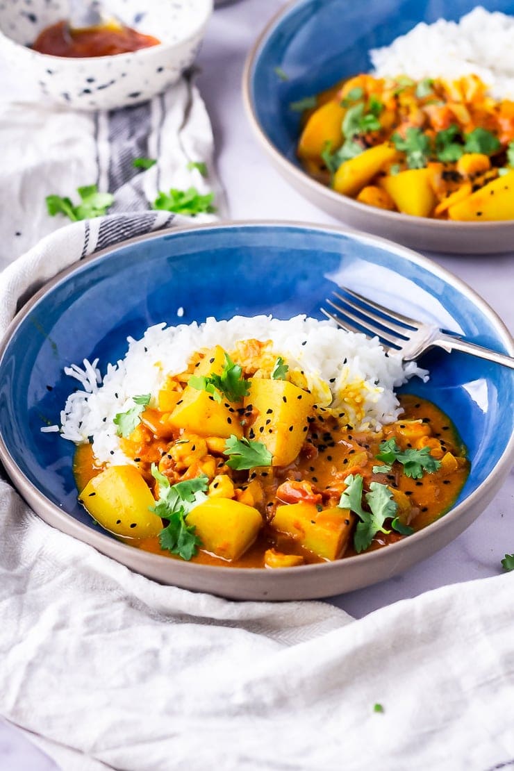 Side angle shot of creamy prawn curry in a blue bowl with a fork 