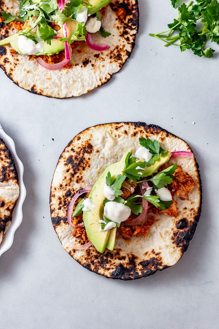 Overhead shot of salmon tacos on a grey background