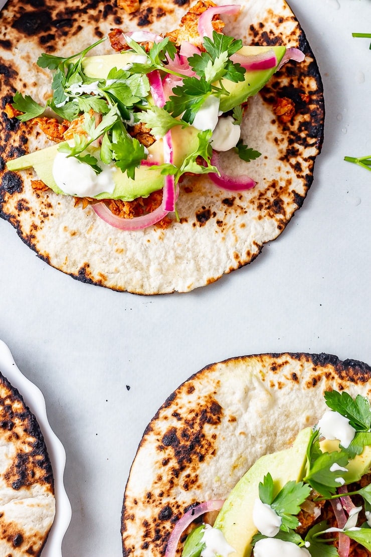 Overhead shot of salmon tacos on a grey background