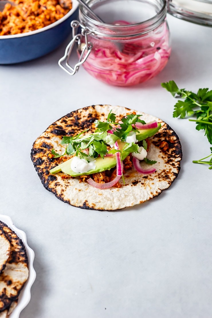 Salmon tacos on a grey background with quick pickled onions