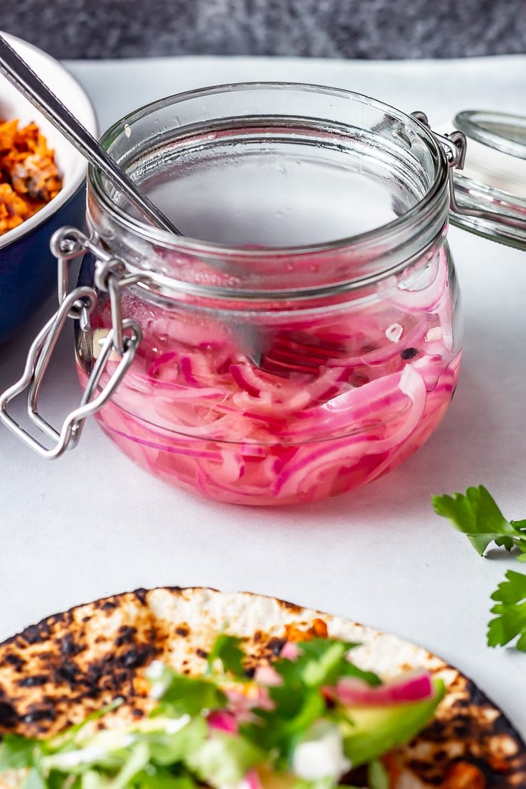 Quick pickled onions for salmon tacos in a jar on a grey background