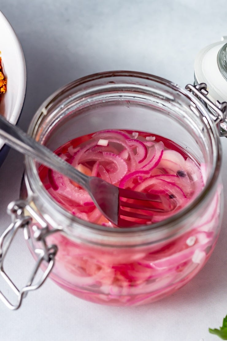 Jar of pickled onions for salmon tacos on a grey background