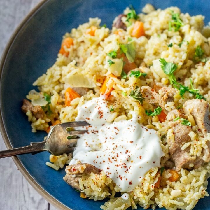 Leftover turkey pilaf in a blue bowl with a fork on a white wooden background
