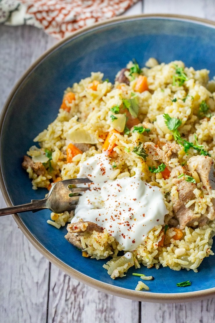 Leftover turkey pilaf in a blue bowl with a fork on a white wooden background