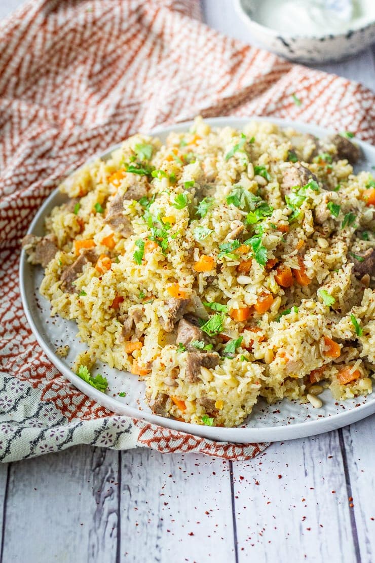 Side angle shot of leftover turkey pilaf on a platter on a white wooden background