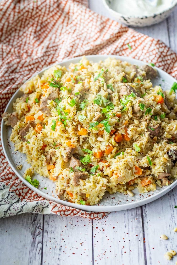 Platter of leftover turkey pilaf on a patterned cloth and a white wooden background