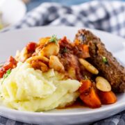 Side angle shot of vegetarian sausage casserole with mashed potato in a white bowl