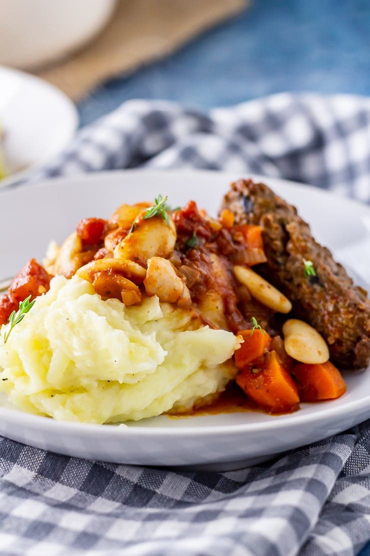 Side angle shot of vegetarian sausage casserole with mashed potato in a white bowl