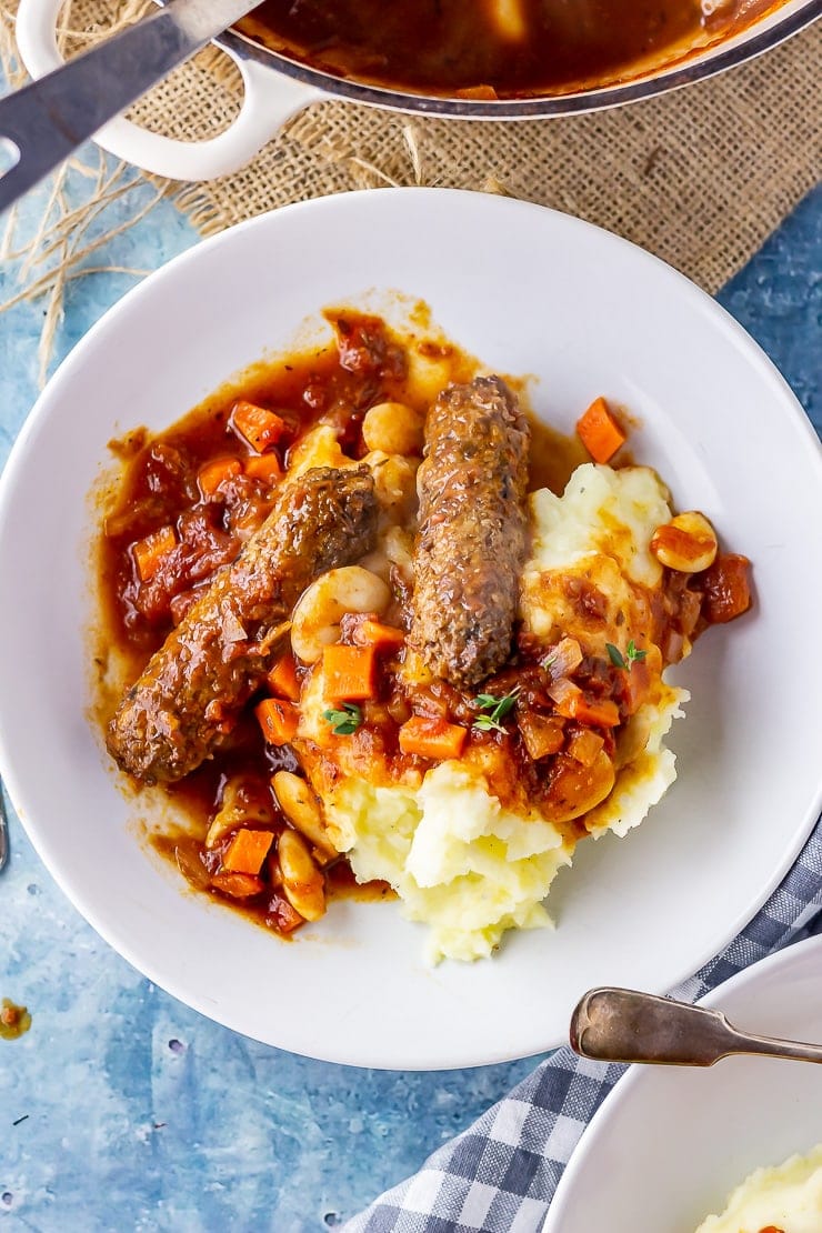 Overhead shot of vegetarian sausage casserole with mash in a white bowl