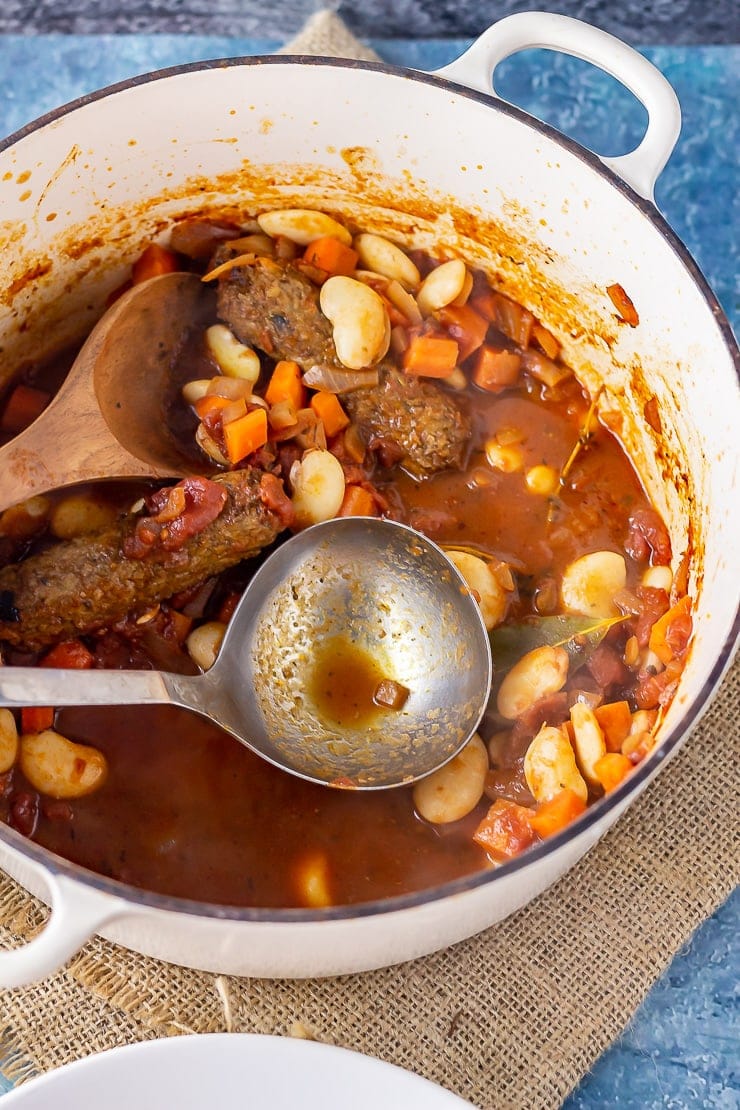 Vegetarian sausage casserole in a white casserole dish with a ladle