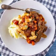 Overhead shot of vegetarian sausage casserole with mashed potato in a white bowl