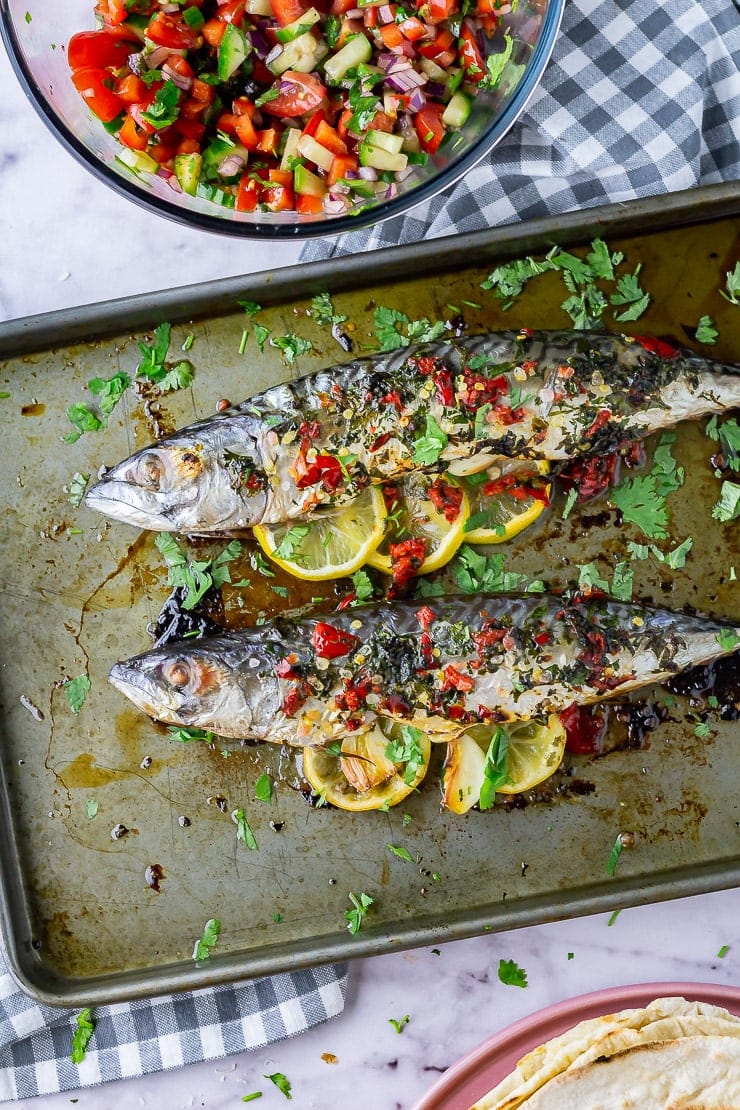 Overhead shot of baked mackerel on a baking sheet on a marble background