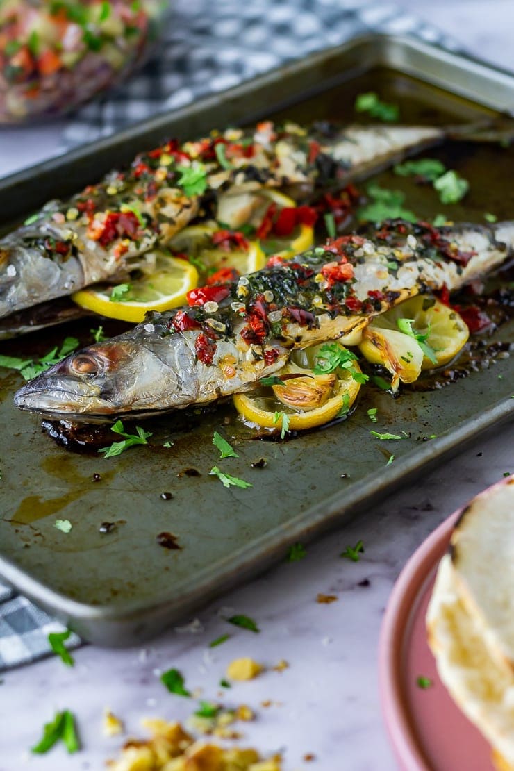 Side angle shot of baked mackerel on a baking sheet and marble background