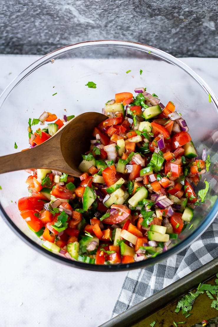 Salad to go with baked mackerel in a glass bowl on a marble background