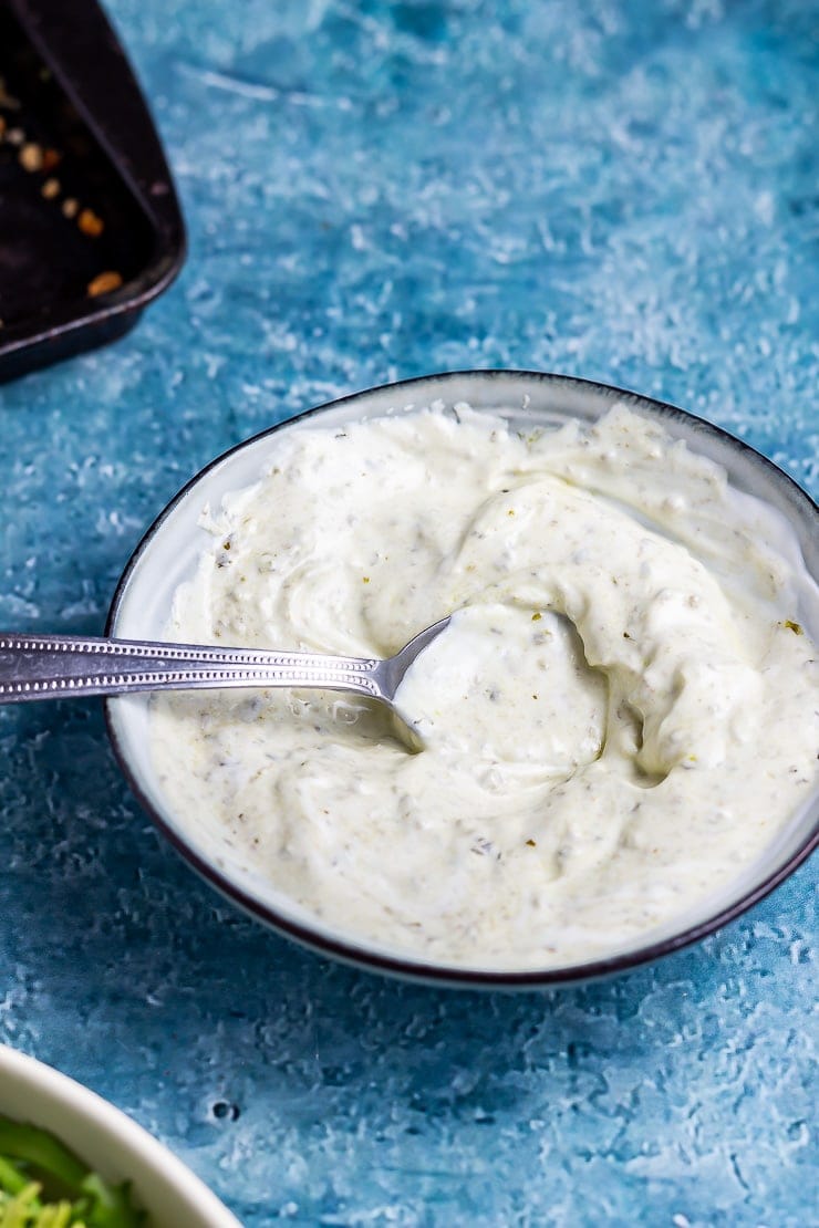 Pesto yoghurt dip for parmesan breaded fish on a blue background