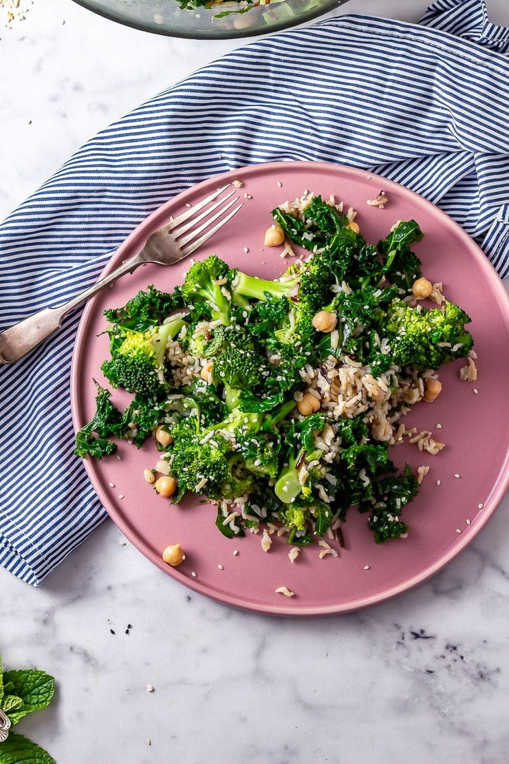 Overhead shot of broccoli and wild rice salad on a pink plate with a striped cloth