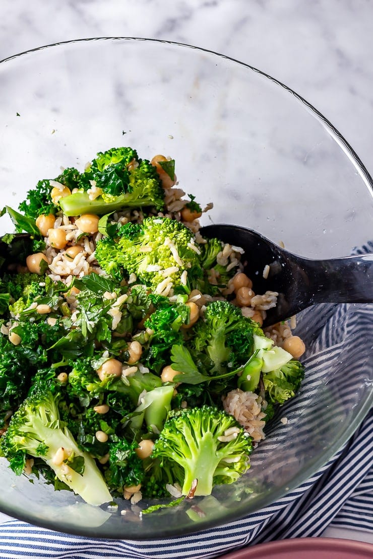 Overhead shot of broccoli and wild rice salad in a glass bowl with a striped cloth
