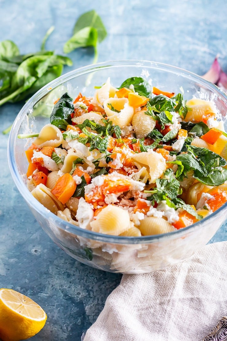 Glass bowl of butternut squash pasta on a blue background