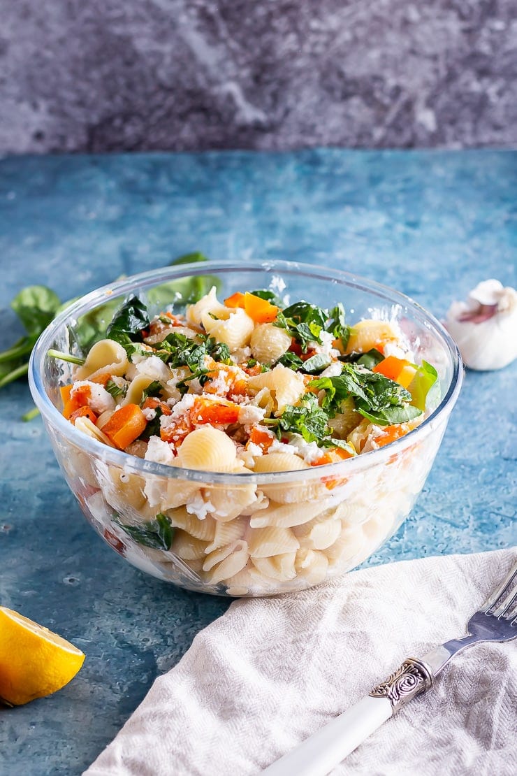 Glass bowl of roasted butternut squash pasta with a light linen and a blue background