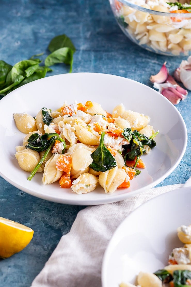 White bowl of butternut squash pasta on a blue background