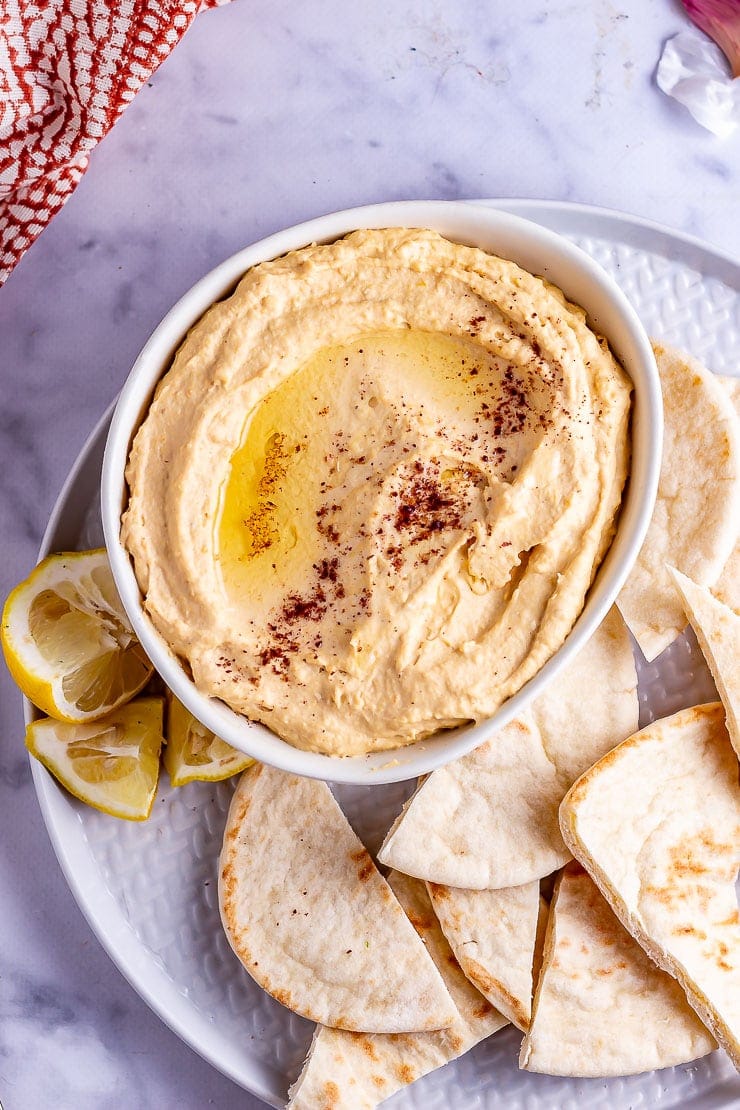 Overhead shot of butternut squash hummus with bread on a marble background