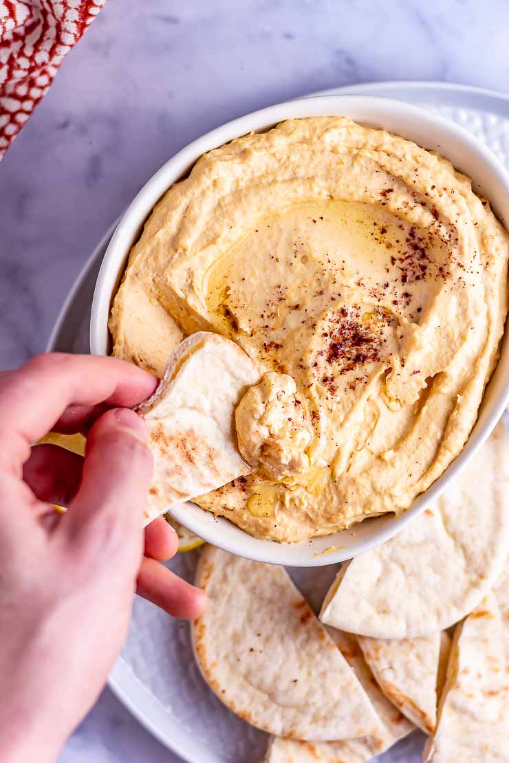 Overhead shot of butternut squash hummus with a hand and bread