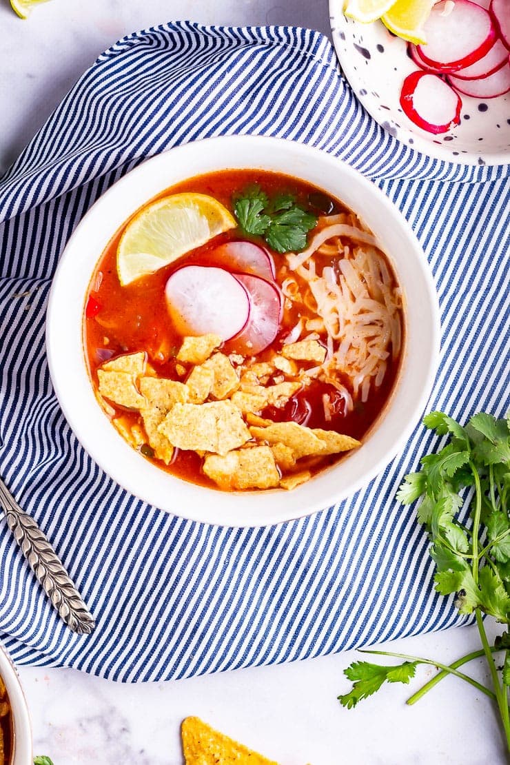 Overhead shot of spicy soup on a striped cloth with coriander