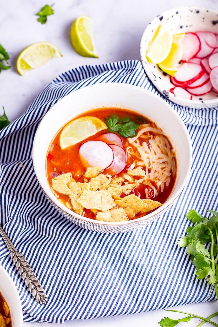Side angle shot of spicy soup in a white bowl on a striped cloth