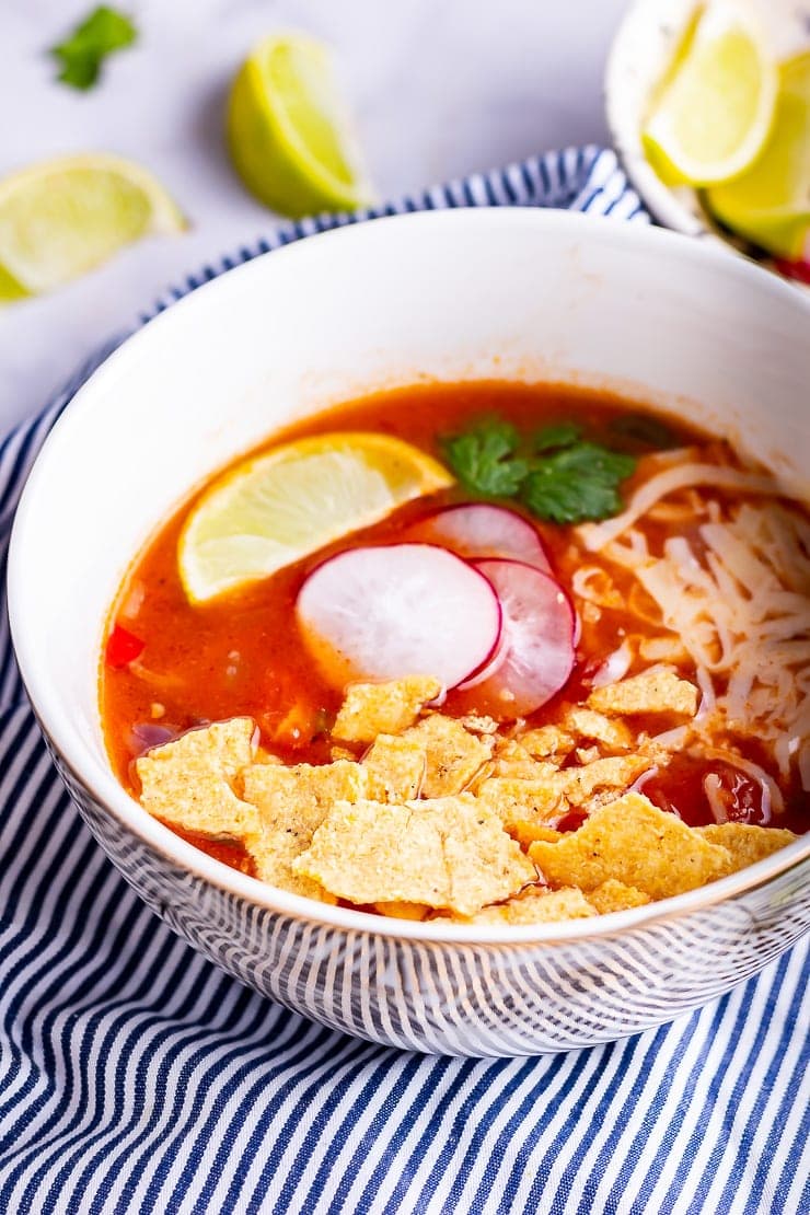 Side on shot of spicy soup with toppings on a striped cloth