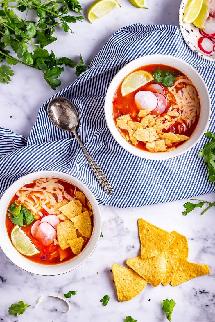 Overhead shot of two bowls of spicy soup on a striped cloth