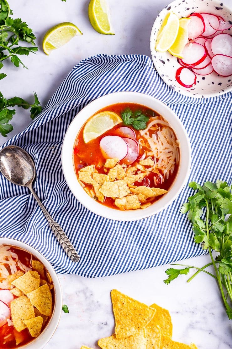 Overhead shot of a bowl of spicy soup with toppings and a striped cloth