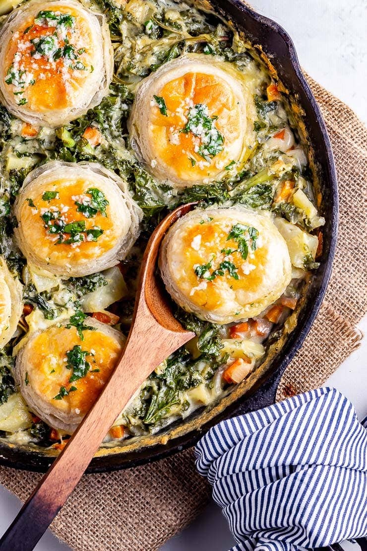 Overhead shot of a spoon in skillet vegetable pie with a striped cloth