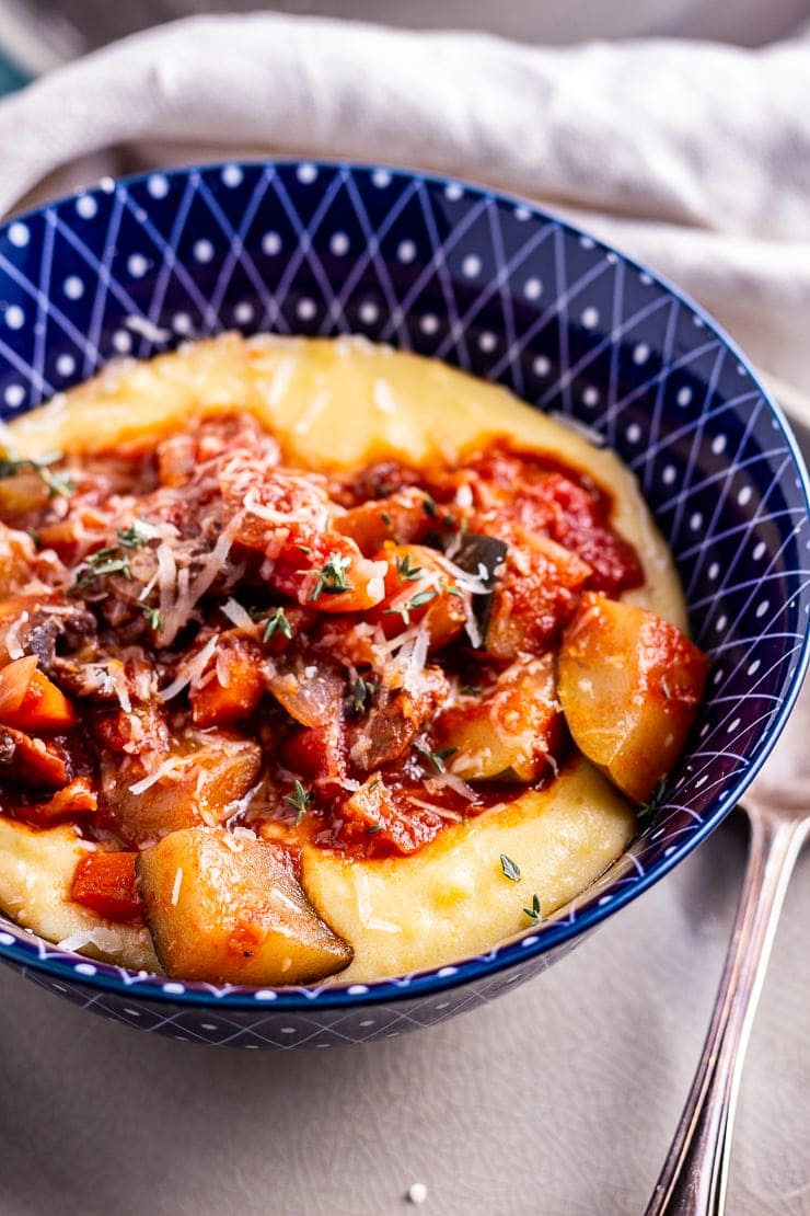 Close up of vegetable stew with creamy polenta in a blue bowl