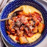 Overhead shot of vegetable stew with creamy polenta in a blue bowl