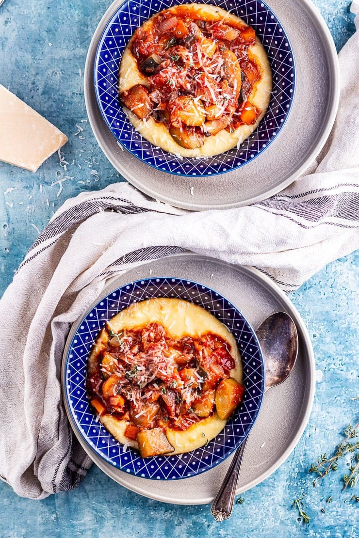 Overhead shot of to bowls of vegetable stew with polenta on a blue background