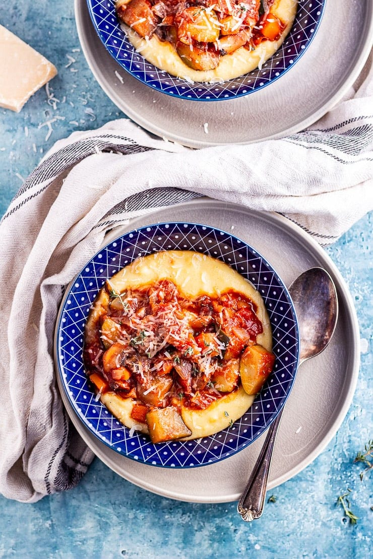 Overhead shot of vegetable stew with polenta in blue bowls on a blue background