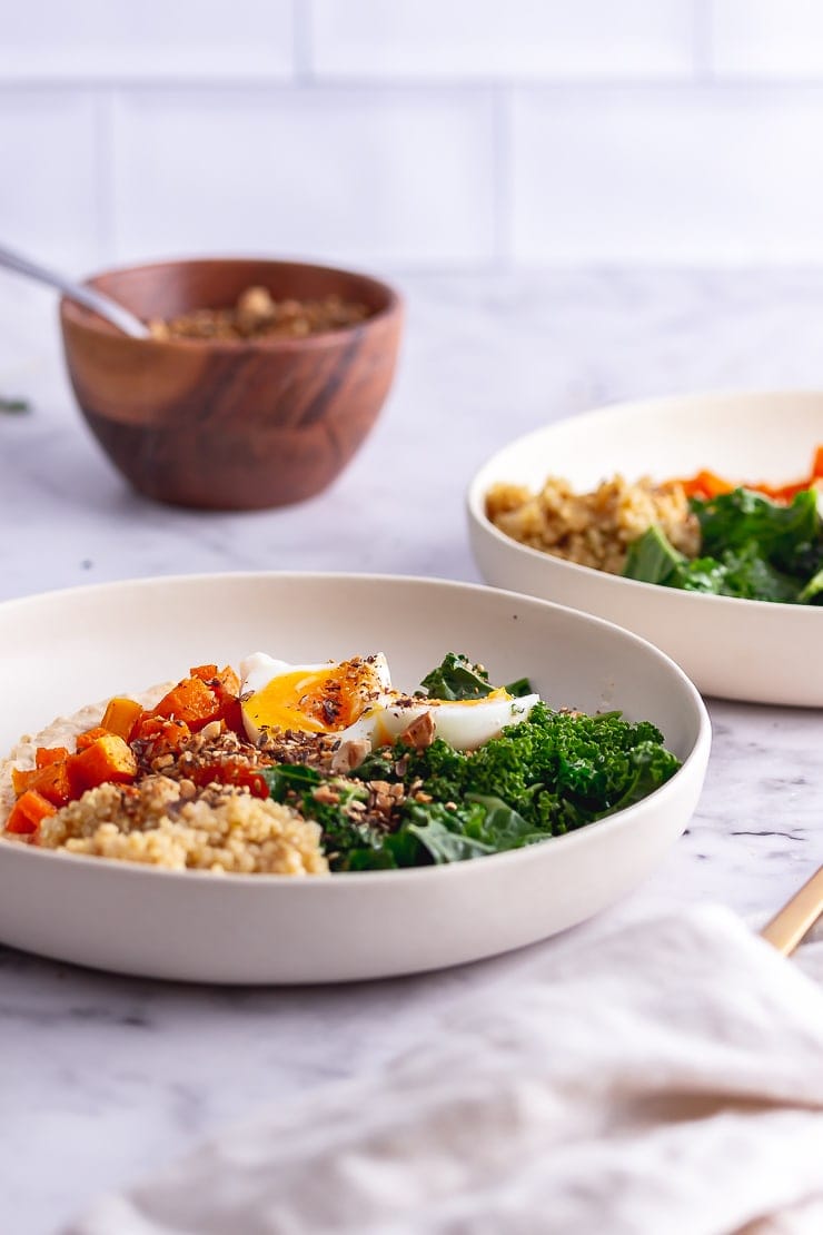 Side on shot of breakfast bowls with a wooden bowl of dukkah in the background